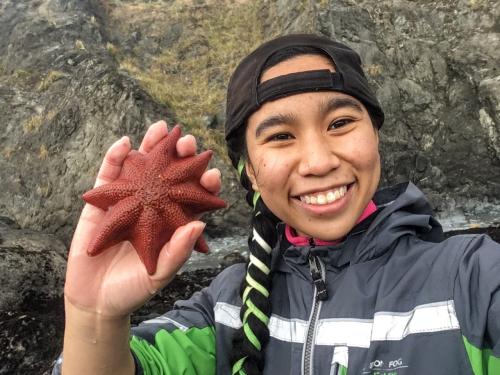 Girl wearing hat smiling with starfish