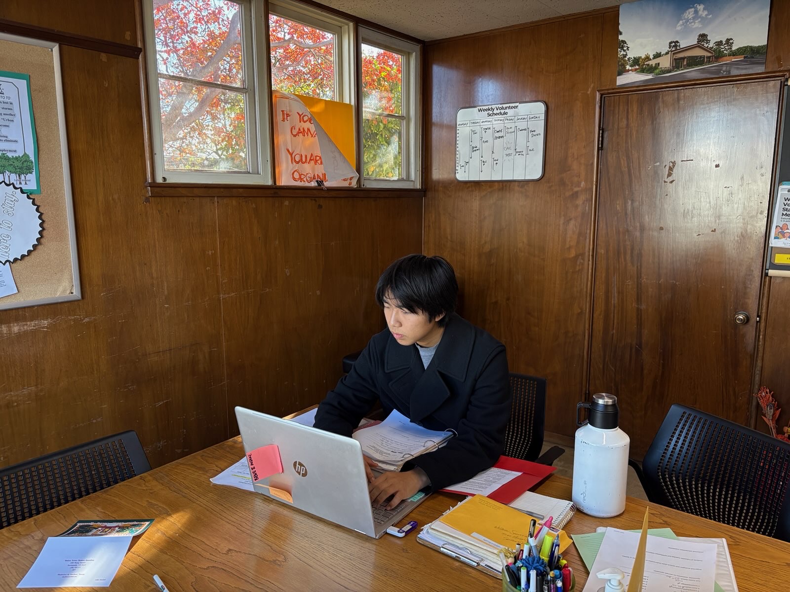 Seito Ezawa sitting at his laptop in a small office room with brown walls and low lighting.