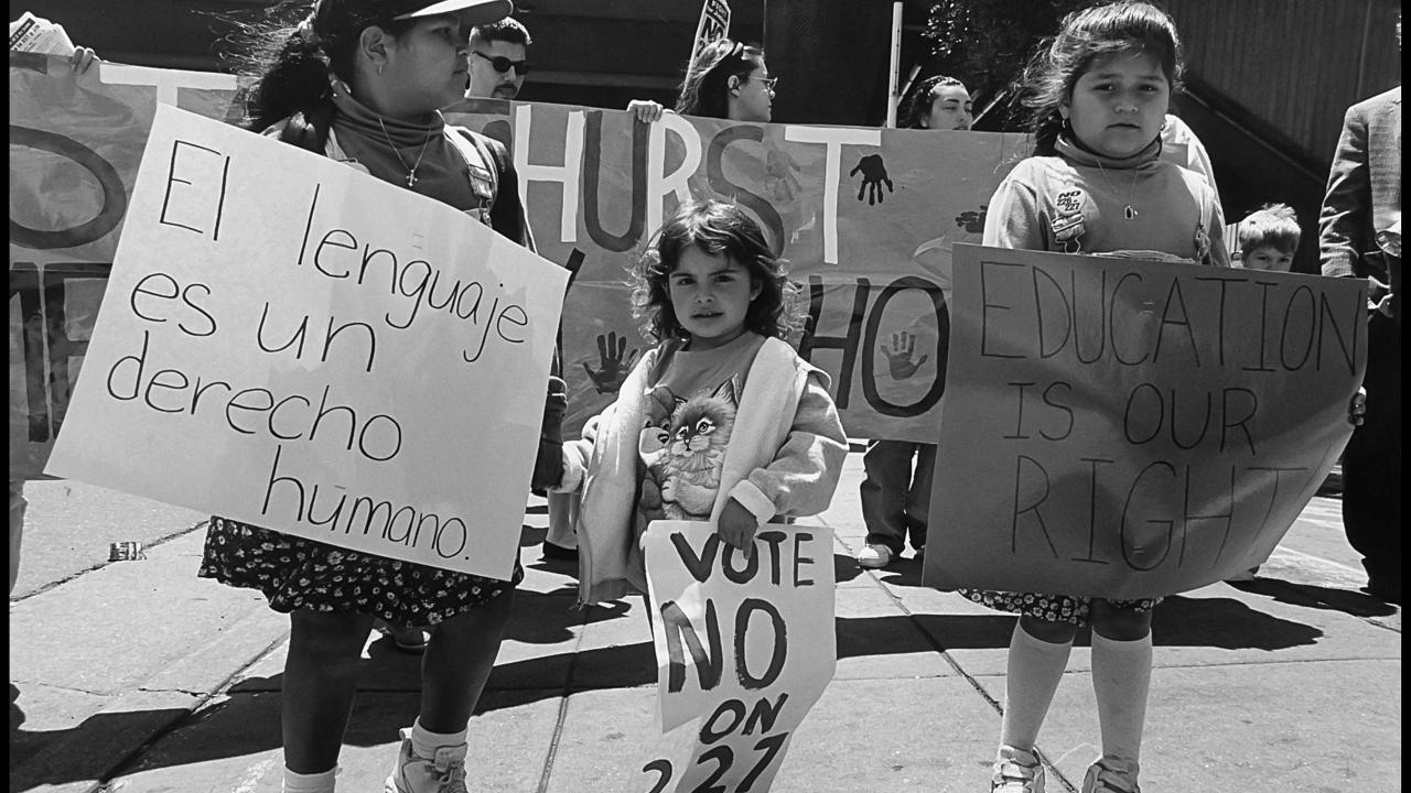 black-and-white photo of children protesting prop 227 "Language is a human right" sign