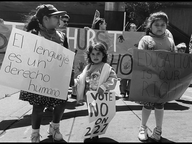 black-and-white photo of children protesting prop 227 "Language is a human right" sign