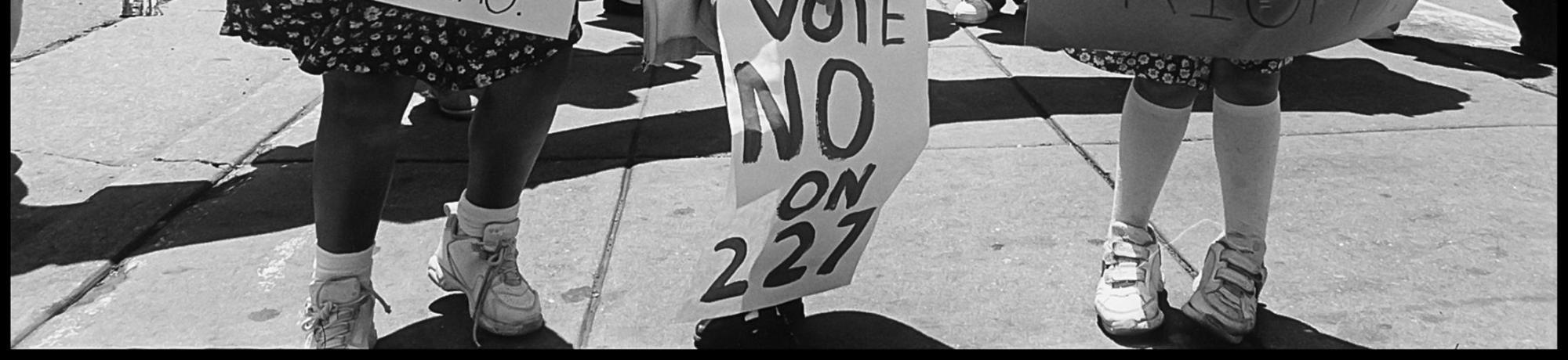 black-and-white photo of children protesting prop 227 "Language is a human right" sign
